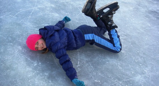 Girl laying down on ice with ice skates on